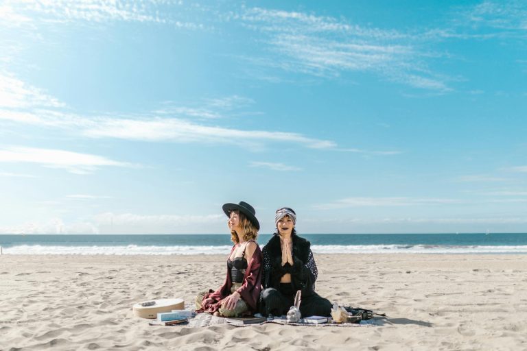 Women practicing meditation and crystal healing on a sunny beach.